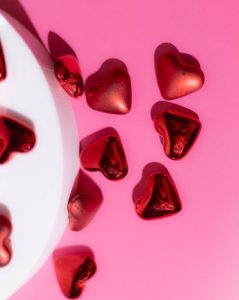 Crvene čokoladne praline u obliku srca na ružičastoj pozadini