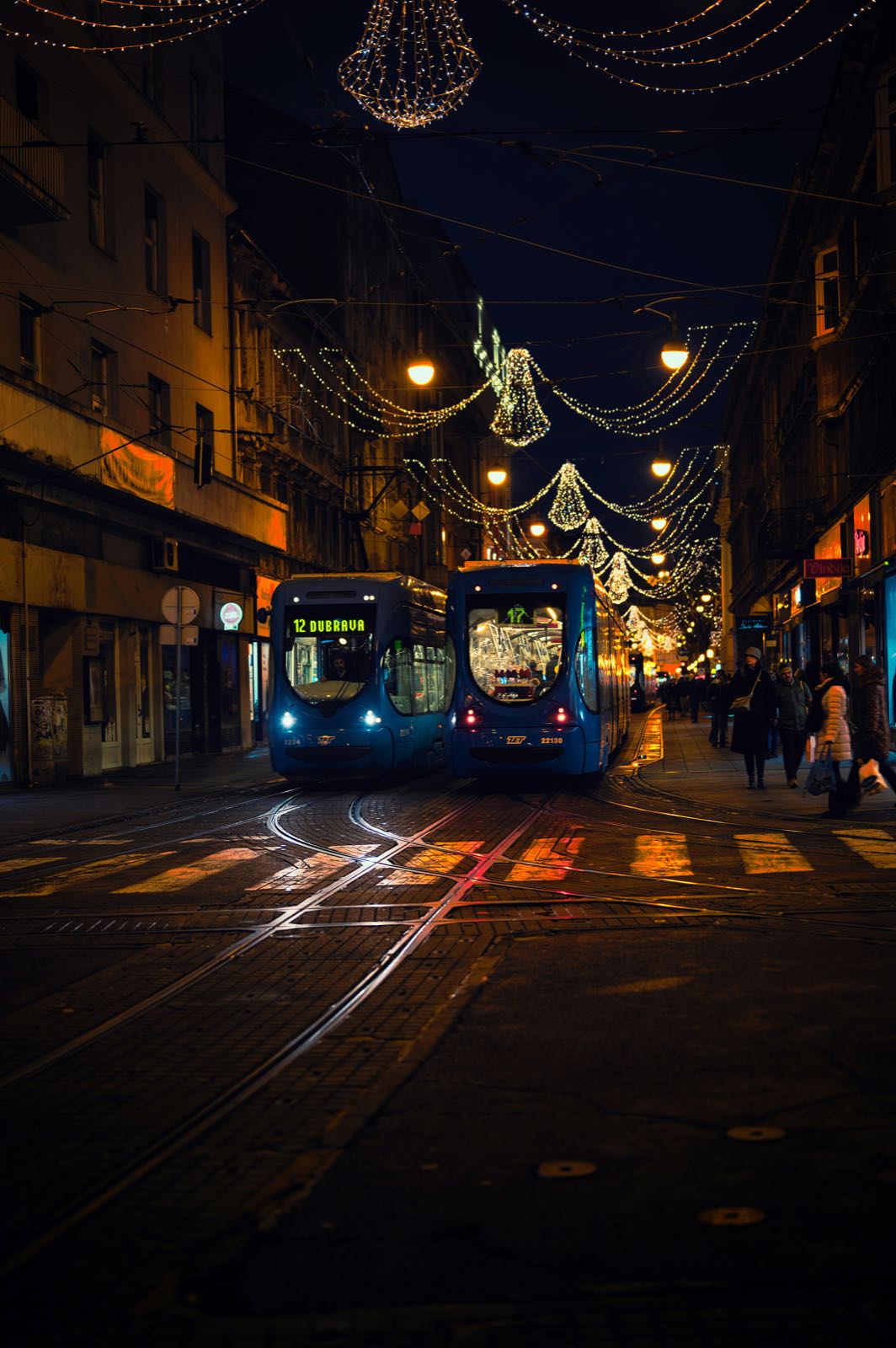 Blue Zagreb trams at night under Advent Christmas lights